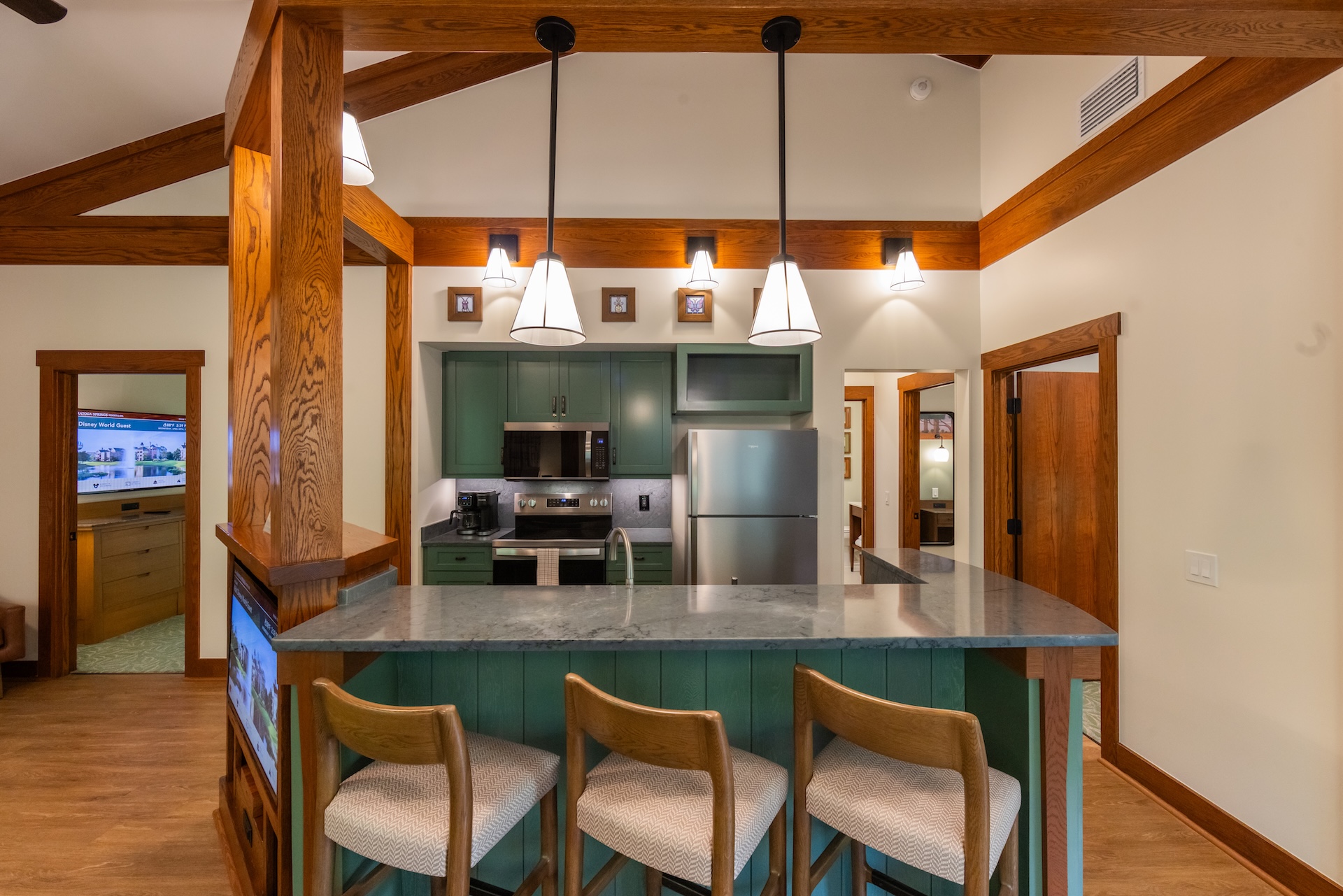 Saratoga Springs new DVC villas. The image showcases a modern kitchen interior featuring a green cabinetry design and a gray countertop bar. Pendant lights hang above the bar area, creating a cozy and inviting atmosphere.