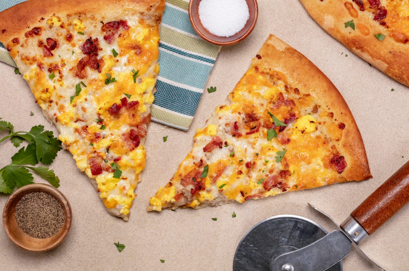 The image showcases several slices of pizza arranged on a light surface. One slice features a topping of scrambled eggs, bacon, and cheese, while the other has similar ingredients with a different arrangement.