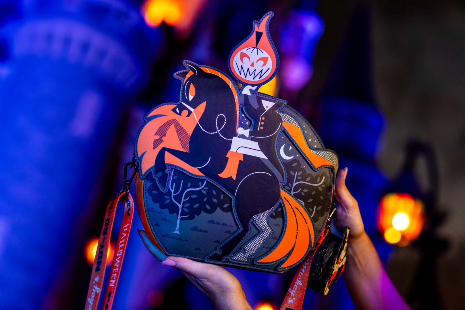 A stylized handbag featuring a graphic design of a horse and rider, with Halloween-themed elements. The background includes a castle silhouette, enhancing the seasonal theme of the image.
