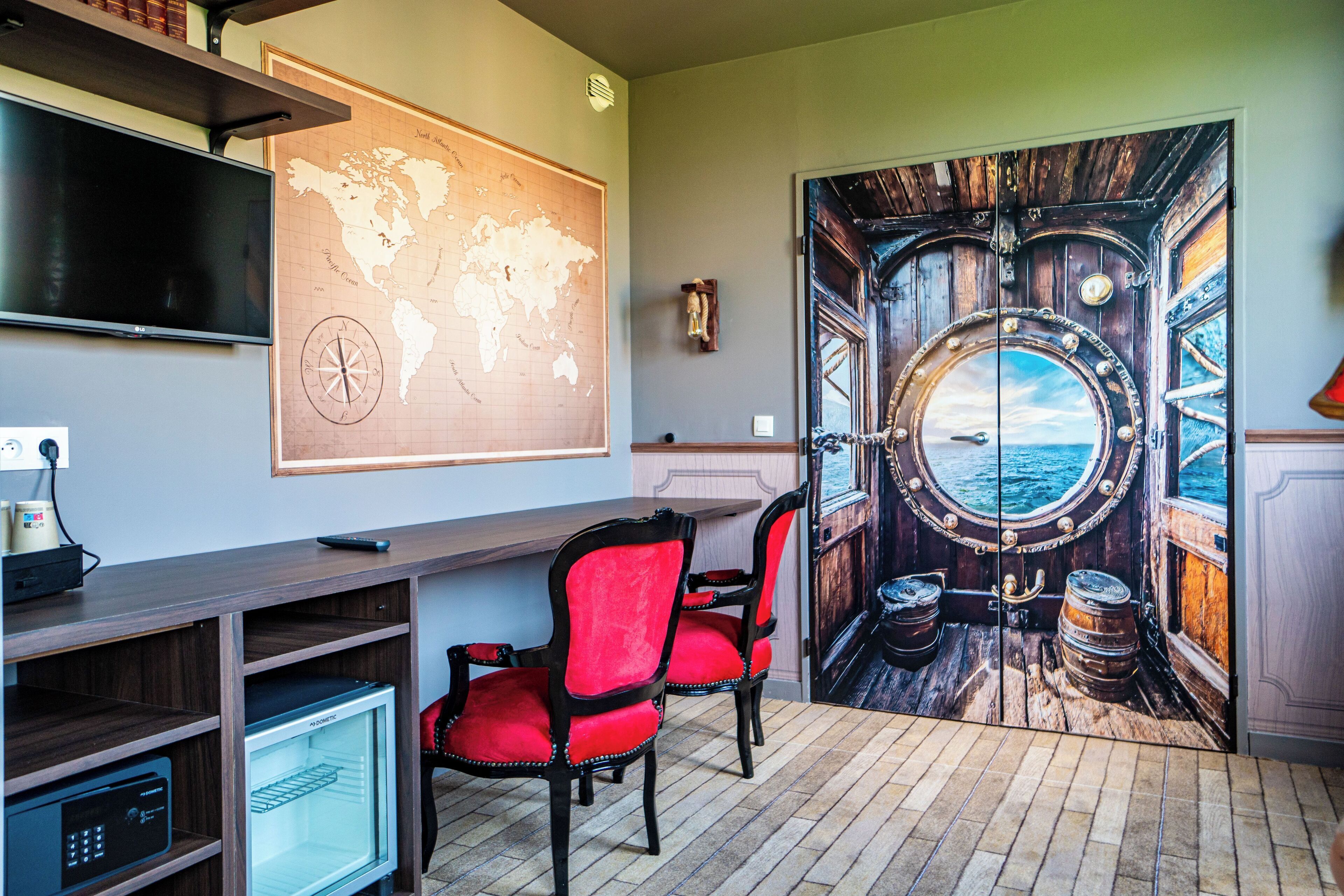 The image depicts an innovative office space designed to resemble a ship cabin. It features a large door mural with a circular porthole view of the ocean, complemented by a world map and modern office furniture.