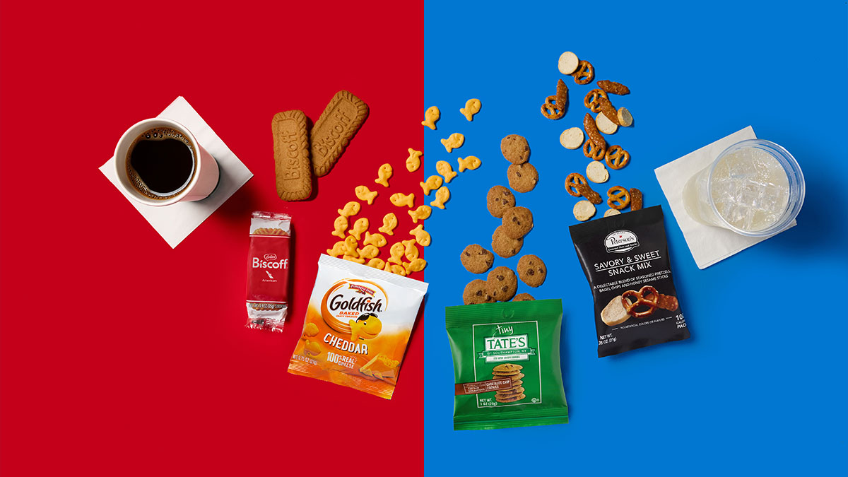 The image features a vibrant split background with assorted snack items placed on either side. On the left, there are coffee, Biscoff cookies, and various snacks, while the right side showcases more snacks and a drink.